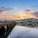 A stone Rennaissance era bridge leading to a coastal town with twinkling lights
